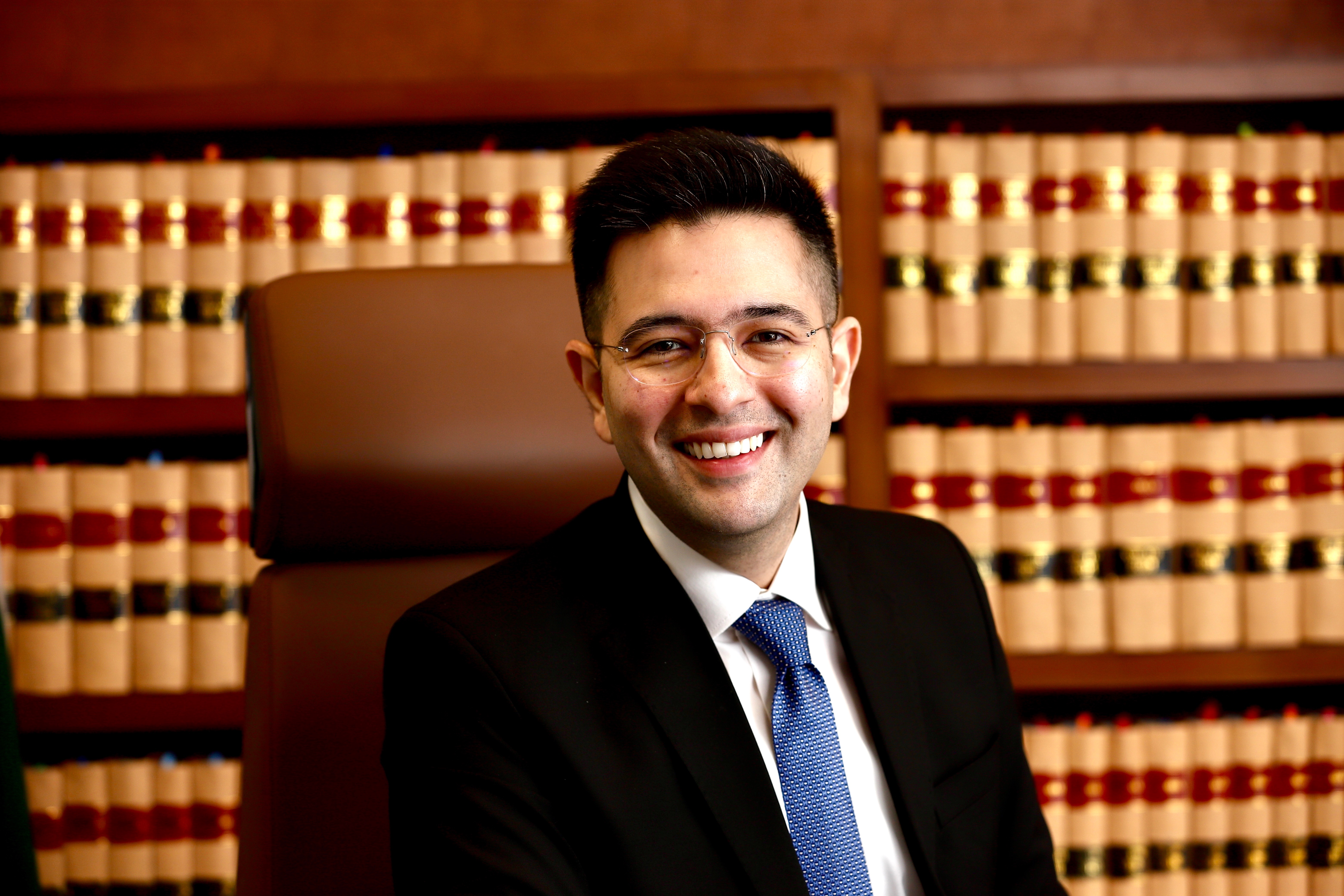 Raghav Chadha in black suit with law books background
